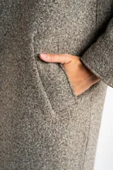 Tapado largo de corte oversize en color beige, con solapas clásicas y cierre frontal con botones. Presenta un diseño minimalista y elegante, ideal para un look sofisticado.