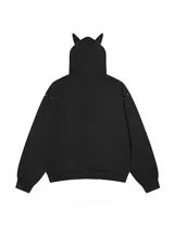 Campera negra con cierre frontal, capucha con orejas decorativas blancas con tachas, y detalles de tachas metálicas en el frente y hombros. Diseño de corte regular.