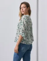 Blusa de gasa con estampado geométrico en tonos negro, gris y celeste. Tiene cuello redondo y mangas 3/4 amplias con abertura y botón.