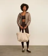 Campera puffer deportiva de mujer, confeccionada en tejido tecnológico ligero con relleno acolchado. Presenta capucha integrada, cierre frontal con cremallera y diseño de manga larga. La prenda destaca por su versatilidad, siendo capaz de transformarse en una pequeña cartera.