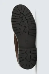 Zapato tipo náutico con diseño de paneles combinados en gamuza marrón y piel con pelo con estampado de vaca. Presenta cordones, horma redonda y suela gruesa con piso track.