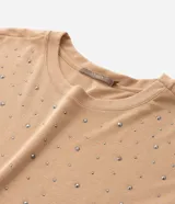 Remera de malla color tostado con cuello redondo, mangas cortas y aplicación de strass salpicado en toda la prenda.