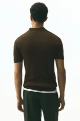 Remera polo de manga corta en punto acanalado fino, color marrón oscuro, con cuello clásico y medio cierre frontal.