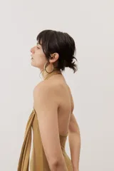 Vestido largo negro de corte al cuerpo con cuello halter y detalle de hebilla metálica dorada en el hombro con tira drapeada.