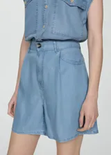 Short de tiro alto color celeste, con cierre de cremallera y botón, trabillas, tejido fluido, detalle de pinzas, diseño corto y dos bolsillos laterales.