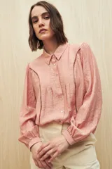 Camisa blanca de manga larga con cuello clásico y botones de nácar. Presenta detalles calados en el frente.