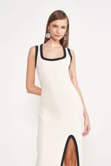 Vestido midi de punto color crema, con escote cuadrado, breteles anchos con ribete negro y abertura lateral en la falda con ribete negro.
