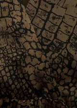 Vestido corto con cuello en V cruzado, mangas largas acampanadas y falda con volantes en el bajo. Presenta un estampado de textura tipo reptil en tonos marrones y negros, con cintura entallada.