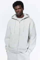 Campera con capucha en felpa de peso medio color gris claro, con interior cepillado suave, cierre y bolsillos delanteros, puños y bajo en punto acanalado. Corte holgado.