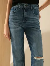 Pantalón de jean de tiro alto, corte recto, color azul medio con lavado parejo y un corte en la rodilla.