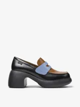 Mocasín de cuero vacuno con diseño bicolor en negro y marrón, destacando una banda frontal en color celeste. Presenta un tacón grueso y plataforma de goma, con plantilla de EVA para mayor amortiguación.