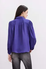 Camisa fluida de manga larga, color negro, con cuello camisero, puño con botón y detalle de frunces.