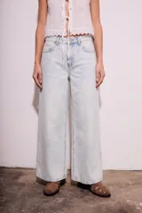 Pantalón de jean con corte wide leg y tiro medio, en color celeste claro con efecto lavado. Presenta diseño de cinco bolsillos y cierre frontal con botón y cremallera.