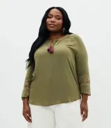 Blusa de viscosa color verde oliva, con cuello redondo, lazo con borlas decorativas y mangas largas con bordado étnico en los puños.
