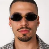 Lentes de sol con diseño ovalado y montura metálica dorada. Cuentan con cristales oscuros y protección UV400.