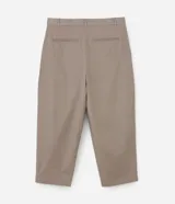 Pantalón de vestir color beige, de corte amplio estilo japonés, con cintura con trabillas, cierre tradicional, pliegues frontales, bolsillos laterales y traseros, y efecto satinado.