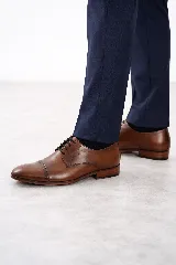 Zapato de vestir acordonado de cuero vacuno marrón, con puntera distinguida y suela con sutil tacón.