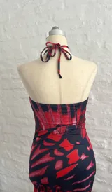 Vestido corto con estampado abstracto en tonos rojo y negro, escote halter con abertura en el pecho y corte ajustado al cuerpo.