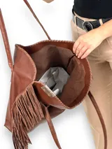 Bolso negro tipo tote de cuero con flecos laterales y etiqueta con logo de la marca.