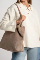 Sweater de tejido de punto color blanco roto o crema, con textura jaspeada. Presenta cuello polo y un escote con tres botones nacarados. El calce es holgado (oversize) y tiene mangas largas.