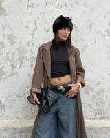 Cinturón trenzado de cuero negro con hebilla metálica circular grande de estilo western.