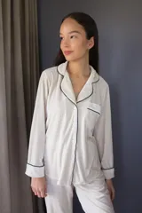 Pijama de tela velvet color beige, compuesto por una camisa de manga larga con botones frontales y vivo en contraste, y un pantalón recto con cintura elástica.