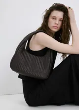 Bolso de mano tipo hobo color marrón oscuro, confeccionado con diseño trenzado y asa integrada.