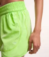 Bermuda deportiva corta de microfibra ligera, color lila, con cintura elástica funcional y textura de agueros.