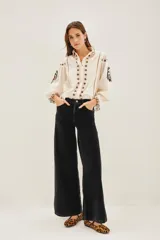 Pantalón estilo jean confeccionado en corderoy de color negro, de corte wide leg, tiro alto y diseño de pernera ancha. Cuenta con bolsillos delanteros aplicados y traseros.