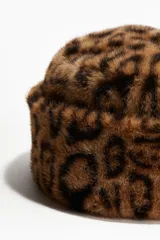 Gorro de estilo bucket con textura de pelo sintético y estampado de leopardo. Presenta un diseño con doblez ancho y forro interior.