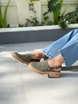 Zuecos de cuero color verde seco, con hebilla lateral y suela de goma.