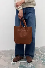 Bolso tipo tote de cuero vacuno con textura granulada, color tostado. Presenta doble asa larga para llevar al hombro y un diseño amplio y minimalista.