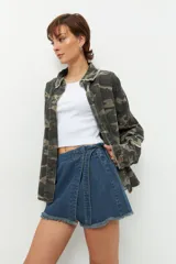 Short pollera de jean prelavado color negro, con lazo en uno de sus laterales y detalle de flecos en las terminaciones.