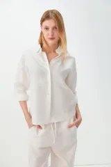 Camisa de corte recto y mangas largas, confeccionada en una mezcla de lino y algodón. Presenta cuello clásico y cierre frontal con botones.