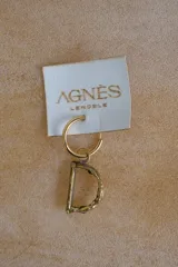 Aro individual dorado con dije colgante en forma de letra "G" con textura irregular.