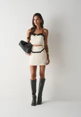 Top de tirantes finos con diseño bicolor, confeccionado en color crudo con detalles en negro en el escote. Presenta un corte ajustado y estilo corset.