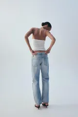 Jeans rectos de tiro medio en denim azul con efecto deslavado. Presentan diseño de cinco bolsillos, cierre frontal con botones metálicos y dobladillo vuelto en el bajo.