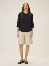 Remera de algodón de color negro con cuello en V y mangas tres cuartos abullonadas, con puños elásticos y detalles de bordado artesanal en las mangas.