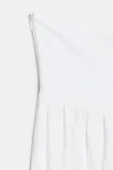 Vestido midi de diseño strapless con escote recto. Presenta un cuerpo superior blanco con textura fruncida y una falda inferior en tono beige con caída fluida.