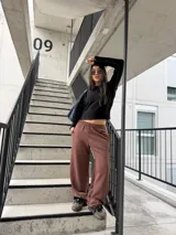 Pantalón deportivo estilo baggy de mujer, color chocolate, con cintura elástica y una línea lateral blanca.