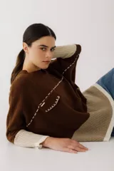 Buzo de lana color beige con bloques de color ocre y bordó en mangas y ruedo. Presenta un bolsillo pequeño en el pecho y costuras decorativas en color bordó.