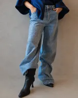 Jean de corte holgado y tiro medio, confeccionado en denim de lavado claro con aplicación de strass en toda la superficie. Presenta diseño de cinco bolsillos y cierre frontal con botón metálico.