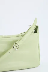 Bolso crossbody de efecto cuero en color negro, con diseño compacto, cierre superior y correa ajustable con hebilla metálica.