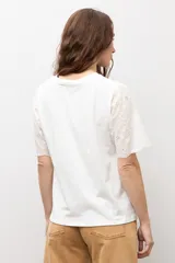 Remera blanca de manga corta con tejido de broderie, cuello redondo y diseño holgado.
