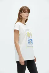 Remera de algodón color beige, de cuello redondo y manga corta con vuelta fija. Presenta un estampado frontal con la leyenda 'Fruit of The Soul' y un diseño de frutillas con un moño verde.