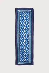 Pareo corto con diseño de hojas de palma en tonos azules sobre fondo claro, con bordes en azul oscuro y detalles en rojo.