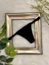 Tanga regulable de lycra negra con entrepierna de algodón y detalle de puntilla en la parte superior.