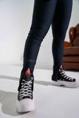 Calza deportiva de tiro alto en color negro, confeccionada en tejido técnico con acabado ligeramente brillante y aberturas en el ruedo.