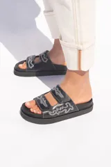 Sandalias negras de cuero vacuno con plataforma de goma y suela ergonómica forrada en cuero. Presentan dos tiras ajustables con velcro y bordado a contratono.