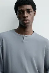 Camiseta relaxed fit de manga larga confeccionada en tejido waffle con mezcla de algodón y cáñamo. Presenta cuello redondo con cierre frontal parcial de botones.